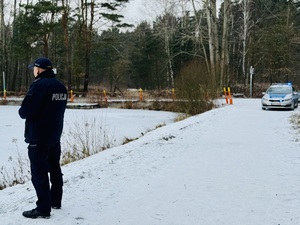 Zdjęcie przedstawia policjanta w czasie kontroli zbiornika wodnego