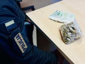 Zdjęcie przedstawia policjanta z zabezpieczonymi rzeczami