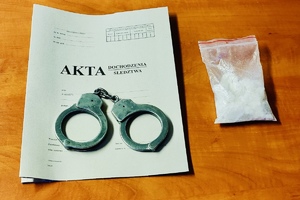 Kajdanki oraz zabezpieczone narkotyki leżą na aktach sprawy