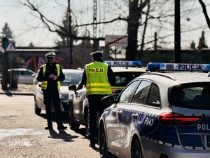 Policjanci obok radiowozów podczas działań