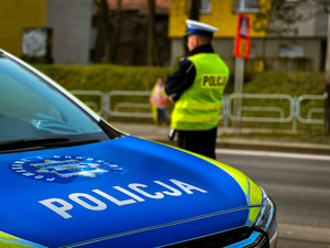 Policjant przy radiowozie w rejonie przejścia dla pieszych