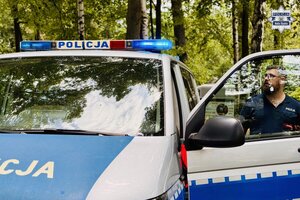Policjant włącza sygnały świetlne w radiowozie