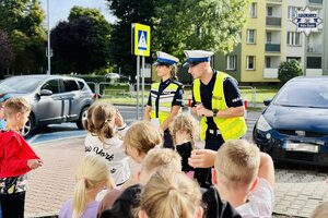 Policjanci ruchu drogowego ćwiczą z dziećmi przechodzenie przez jezdnię