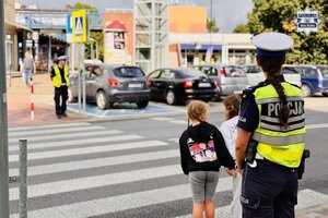 Policjanci ruchu drogowego ćwiczą z dziećmi przechodzenie przez jezdnię