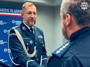 zdjęcie z sali odpraw pokazujące komendanta gratulującego wyróżnionemu policjantowi