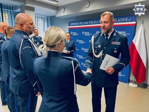 zdjęcie z sali odpraw pokazujące komendanta składającego gratulacje policjantce
