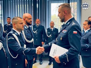zdjęcie z sali odpraw pokazujące komendanta składającego gratulacje policjantowi