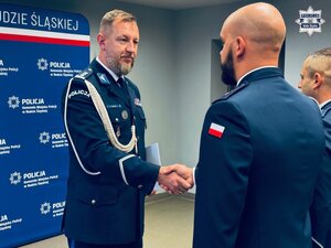 zdjęcie z sali odpraw pokazujące komendanta składającego gratulacje policjantowi