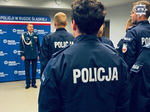 zdjęcie z sali odpraw pokazujące stojących policjantów, w tle widoczny komendant zwracający się do wyróżnionych funkcjionariuszy