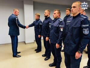 zdjęcie z sali odpraw pokazujące komendanta gratulującego wyróżnionym policjantom stojącym w szeregu