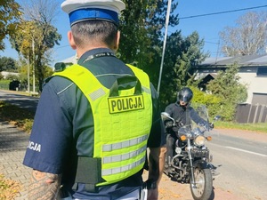 zdjęcie przedstawia policjanta i motocyklistę w trakcie kontroli drogowej