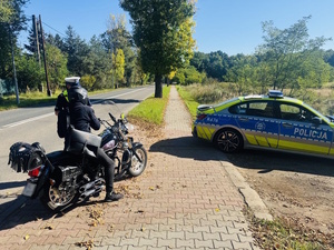 zdjęcie przedstawia policjanta i motocyklistę w trakcie kontroli drogowej