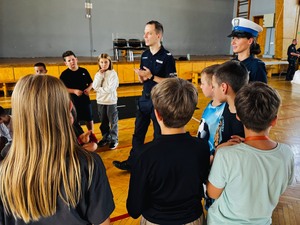 policjanci stoją z uczniami opowiadając im o bezpieczeństwie