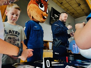 policjant i maskotka wiewiórka pokazują dzieciom akcesoria używane przez policjantów