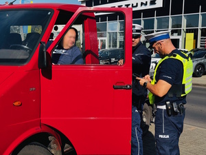 policjanci kontrolujący czerwony samochód dostawczy
