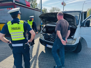 policjanci i kierowca przy samochodzie z otwartą pokrywą silnika