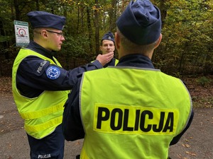 stojący policjanci, jeden pokazuje ręką kierunek poszukiwań